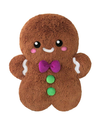 A smiling, plush gingerbread man figure with a purple ribbon and green buttons.
