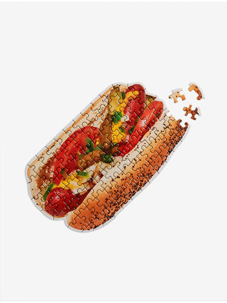 A puzzle of a Chicago style hot dog with three unassembled pieces off to the right.