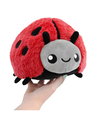 A smiling red, gray and black ladybug held aloft by a hand.
