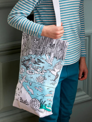 A tote with a pond scene handing from a young person's shoulder.