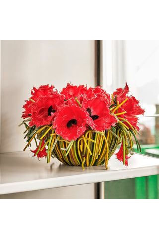 Sitting on a shelf, a vase featuring red poppies and green grasses that make it look natural.